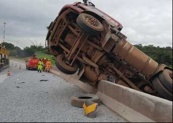 CARRETA CARREGADA COM CIMENTO TOMBA E FICA PENDURADA EM MURETA NA BR-381, EM BETIM